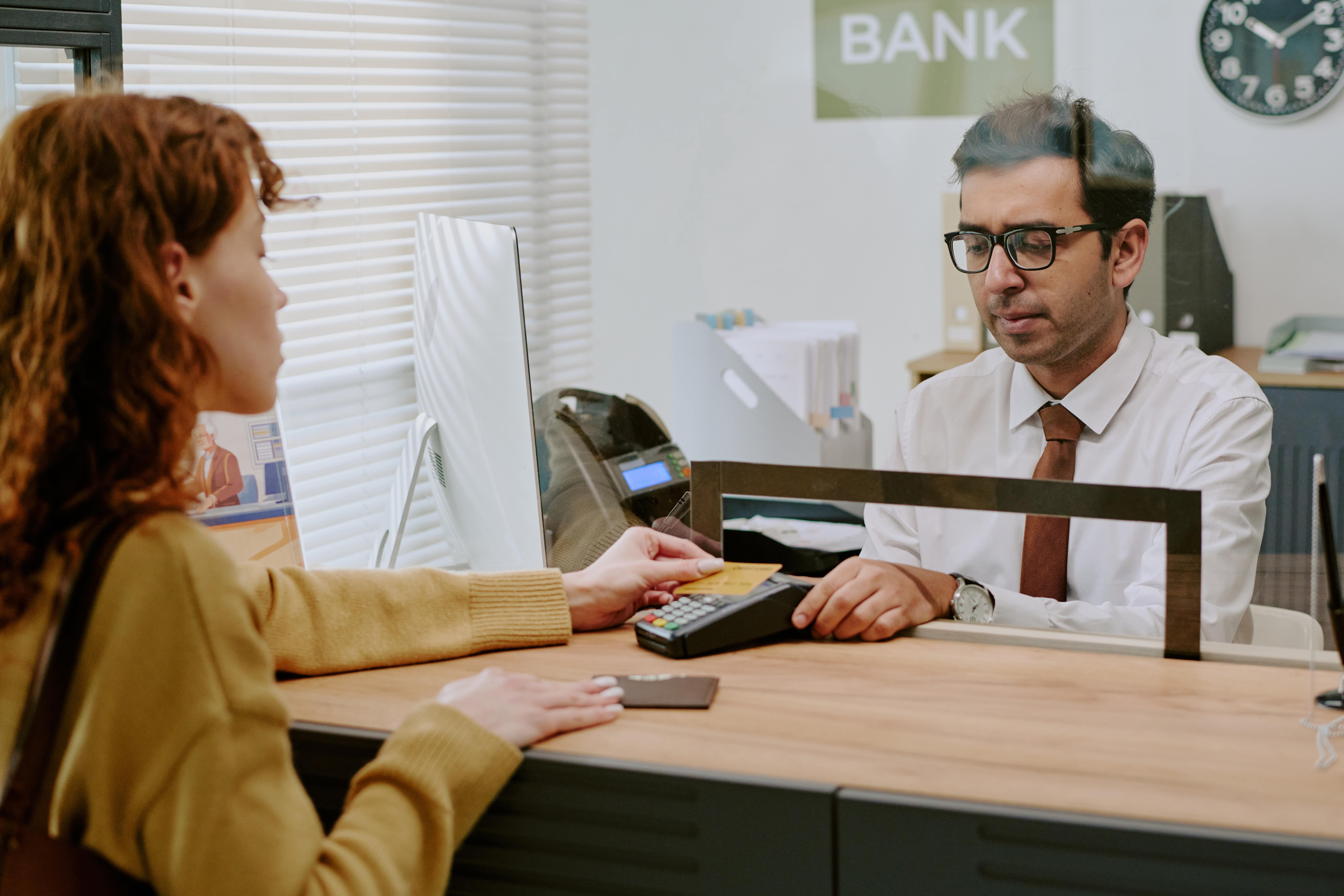 Customer speaking with a bank teller during a transaction at a financial institution